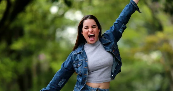 Fun excited happy young woman dancing with joy outside in nature