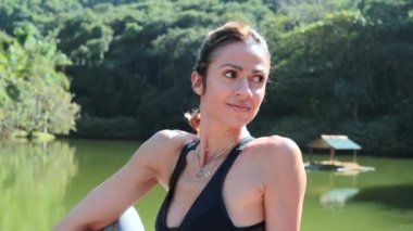 40 'lı yaşlarda bir kadın göl kenarında uzanıyor.