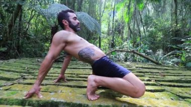 Atletik adam dışarıda yoga eğitimi alıyor.