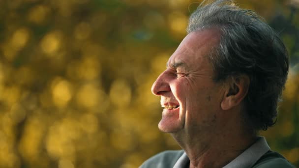 幸せな老人は屋外で笑っている 秋の日差しを楽しむ70代の成人のプロフィール — ストック動画