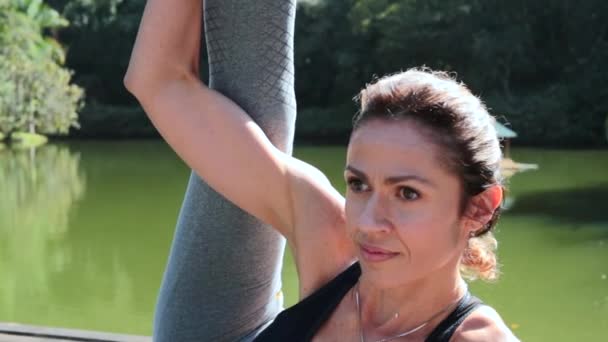 Mujer Estirando Pierna Afuera Por Lago Mujer Entrenando Yoga — Vídeo de stock