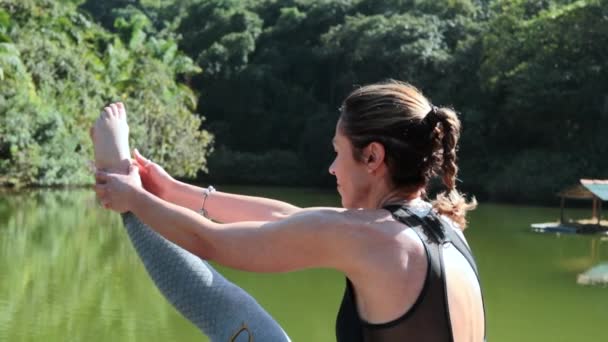 女性でヒーロー40ストレッチボディトレーニングヨガ屋外によって湖 — ストック動画