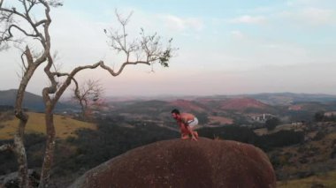 Yoga antrenmanı yapan bir sporcu kayanın tepesinde.