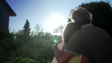 Kollarını birbirlerine dolamış, dışarıda bekleyen son sınıf bir çift. Mutlu evli yaşlı adam ve kadın gün batımında sarılırlar.