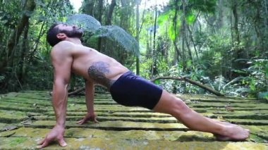 Atletik adam dışarıda yoga eğitimi alıyor.