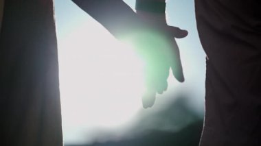 Arka planda güneş ışığının parlamasıyla el ele tutuşun. İki aşık arasındaki güzel romantik an