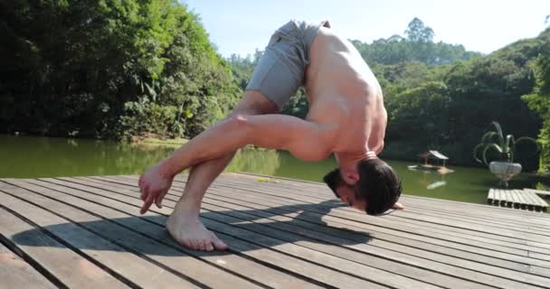 デッキ湖で体を外にストレッチ人 ヨガを練習する男 — ストック動画