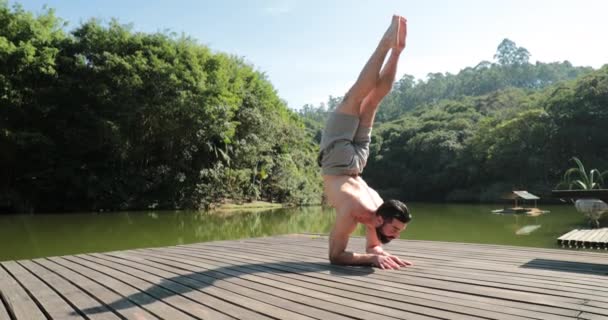 自然の中でヨガを練習する人 腕のスタンドで体を持ち上げる — ストック動画