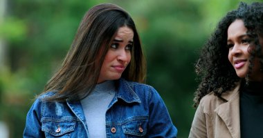 Konuşurken yürüyen ve konuşan kadınlar endişeli görünüyorlar.