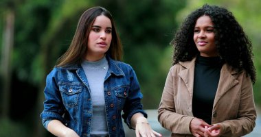 Konuşurken yürüyen ve konuşan kadınlar endişeli görünüyorlar.