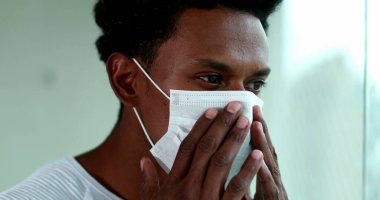 Black man putting on preventive mask during pandemic