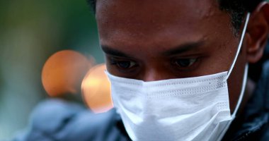 Young black african man wearing face mask outside. close-up