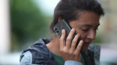 Şehir caddesinde durmuş, dışarıda cep telefonuyla konuşan bir kadın. Kulağında akıllı telefon kullanan kişi
