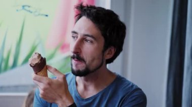 Dondurma yiyen mutlu adam sohbet ederken konuşuyor.