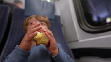 Trende elma meyvesi tutan çocuk.