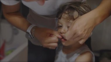 Geceleri diş ipi kullanan küçük bir çocuk. Yatmadan önce diş ipi. Banyoda ayna camının önünde diş sağlığı hijyeni.