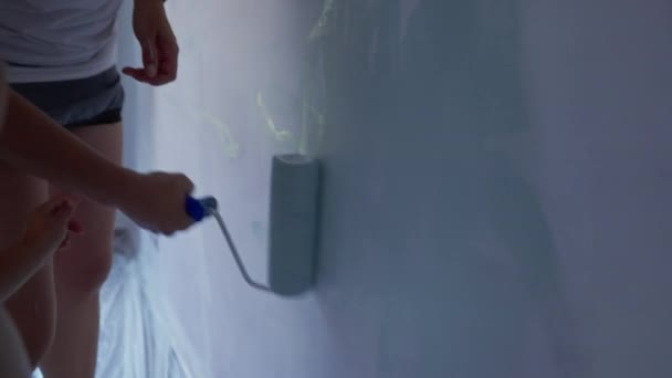 母親と子供の絵の壁 ペイントローラーで家の改装を行う親と子供 アパートの壁にクローズアップ塗料 — ストック動画