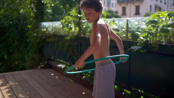 外でフラフープをして楽しい若い男の子 夏休みを日光で楽しむ子供 ケアフリー前の子供 — ストック動画