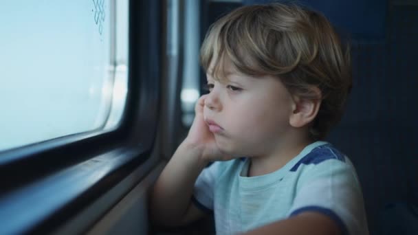電車で旅行する退屈した子供が一人 輸送の退屈を感じる小さな男の子窓の外を見て — ストック動画