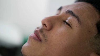 Hispanik genç adam yakından gökyüzüne bakarak dalgın dalgın bakıyor. Güney Amerikalı Brezilyalı meditasyonda gözlerini kapatıyor. Gözlerini açıyor ve gülümsüyor.