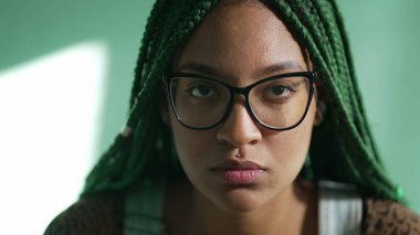 Latin kökenli genç bir Latin kadın kameraya ciddi bir ifadeyle bakıyor. Kendine güvenen Güney Amerikalı yetişkin bir kızın portresi