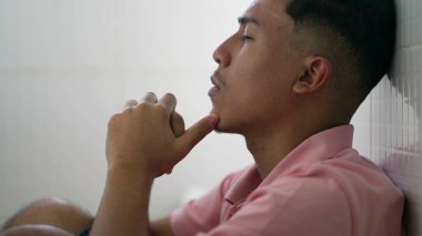 Endişeli genç İspanyol adam zihinsel sorunlar yaşıyor. Bunalımda olan Güney Amerikalı erkek çaresiz zamanlarda evde yerde oturuyor.