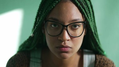 Latin kökenli genç bir Latin kadın kameraya ciddi bir ifadeyle bakıyor. Kendine güvenen Güney Amerikalı yetişkin bir kızın portresi