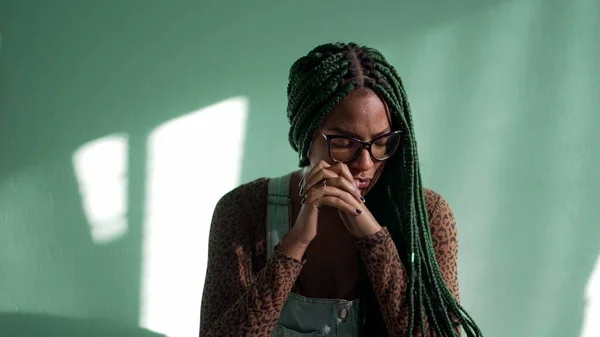 Preoccupied young African American adult girl with box braids. One worried stressed thoughtful female black girl reflecting decision. Dilemma emotion