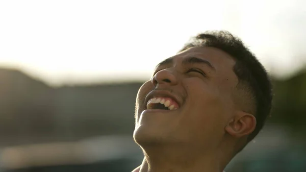 一人の恍惚とした若いヒスパニック系の男が希望と信仰に笑みを浮かべて空に頭を回す カリスマ的なラテン人笑いと喜びを感じる — ストック写真