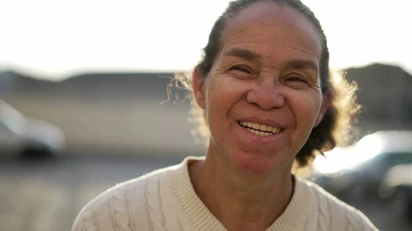 Neşeli İspanyol asıllı yaşlı kadın portresi gülümsüyor ve gülüyor. Mutlu doğal Güney Amerikalı son sınıf öğrencisi dışarıda dikiliyor.