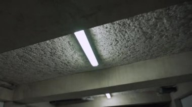 Yeraltı garajının floresan lambaları beton tavanda. Bina otoparkı