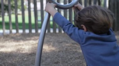 Çocuk oyun parkında dönüyor. Küçük bir çocuk paslanmaz çelik oyuncakla oyun alanında eğleniyor. 