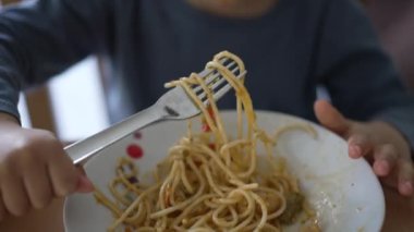 Küçük şirin bir çocuk spagetti yiyor. Çocuk tek başına erişte yiyor. 2 yaşındaki çocuk öğle yemeği yiyor.