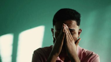 Çaresiz genç adam umutsuzluk ve umutsuzluk hissediyor. İspanyol bir Güney Amerikalı, ağlayarak yüzünü kapatıyor.