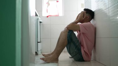 Yerde oturan bunalımlı bir adam. Alnını tutan mutsuz insan zihinsel hastalıktan muzdarip.