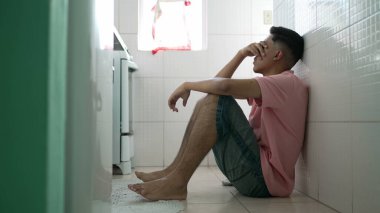 Yerde oturan bunalımlı bir adam. Alnını tutan mutsuz insan zihinsel hastalıktan muzdarip.