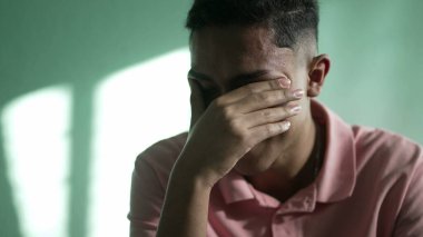 Çaresiz genç adam umutsuzluk ve umutsuzluk hissediyor. İspanyol bir Güney Amerikalı, ağlayarak yüzünü kapatıyor.