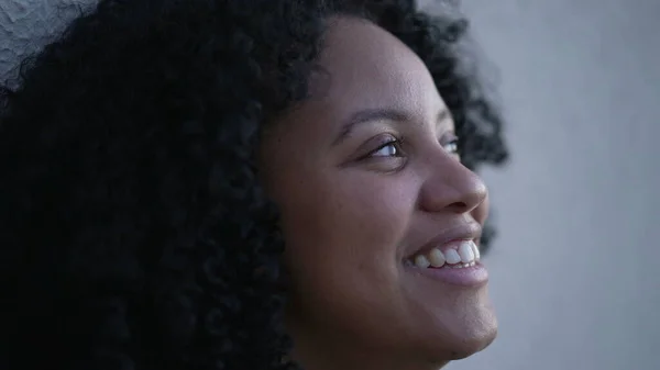 A contemplative young black latina woman closing eyes in meditation. A pensive Brazilian adult girl opening eyes smiling