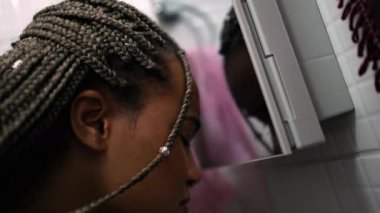 Genç siyah Latin kadın aynada kendine bakıyor..