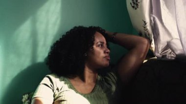 Evdeki kanepede oturan düşünceli siyah bir kadın. Afrikalı bir Amerikalı hayatı düşünüyor..