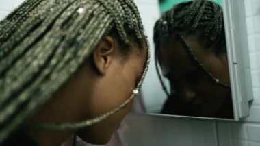 Bin yıllık siyah Latin bir kız zor zamanlarda aynada kendine bakıyor.