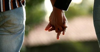 Gün batımında dışarıda el ele tutuşan iki kişi.