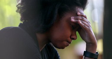 Hüsrana uğramış siyah kadın pişmanlıkla başını sallıyor.