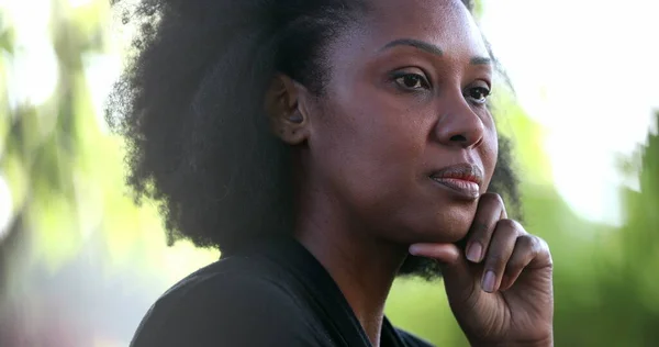 Meditative black woman thinking portrait face close-up, hand in chin