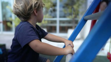 Dışarıda çocuk merdivenine tırmanıyor. Küçük çocuk dışarıda oynuyor.