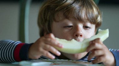 Yeşil karpuz meyvesi yiyen çocuk sağlıklı abur cubur yiyor.