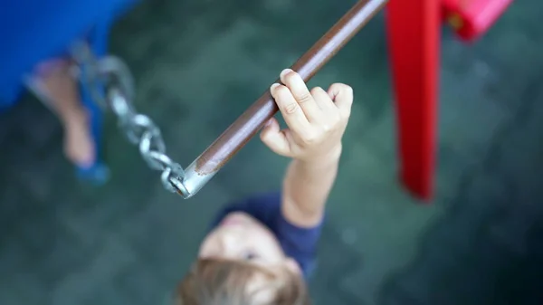 Child trying to reach metal bar at playground kid showing effort reaching for monkey bar