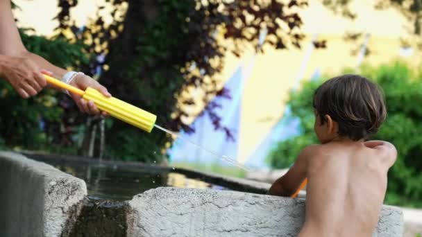 여름에 밖에서는 장난감 싸움을 아이들에게 뿌리고 있습니다 아이가 휴일을 즐기다 — 비디오