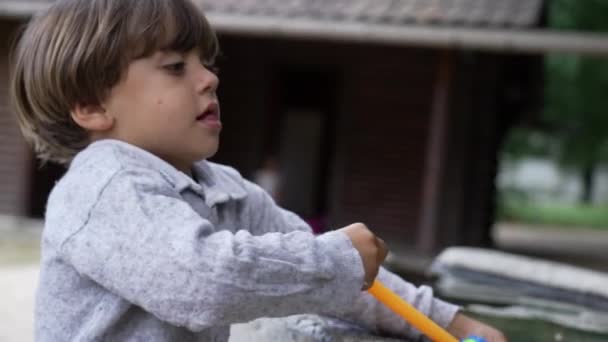 Ένα Μικρό Αγόρι Ψεκάζει Νερό Όπλο Αφρού Παιχνιδιών Έξω — Αρχείο Βίντεο