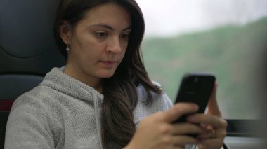 Trenle seyahat ederken mesaj atan bir kadın. Modern teknolojiyi kullanarak işe gidip gelen ya da okuyan yolcular. Akıllı telefon aygıtında yazan kişi